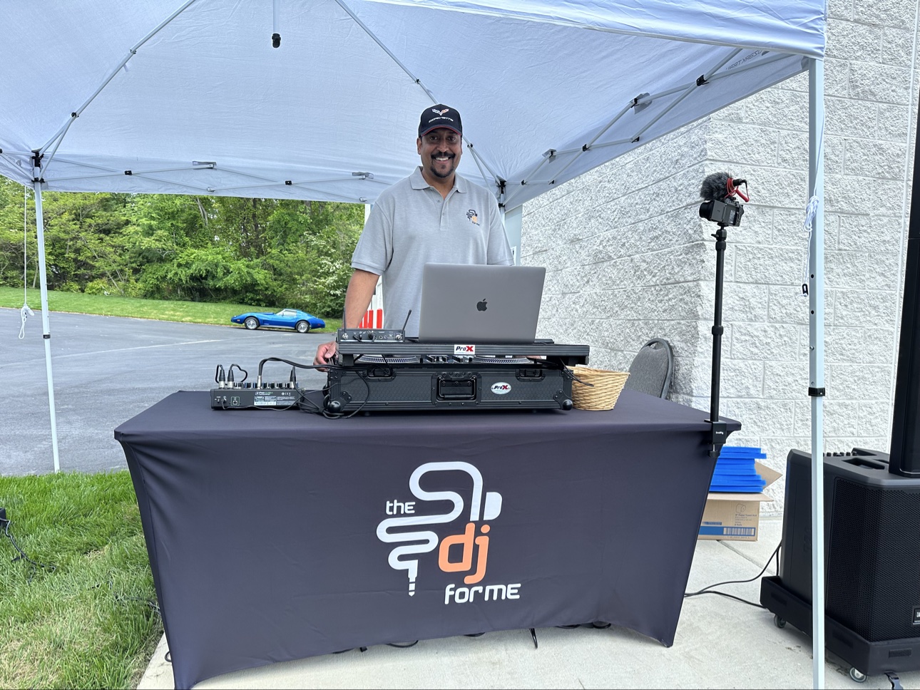 Ferrell Solomon (DJ Solo) smiling behind his branded The DJ For Me booth at an outdoor event